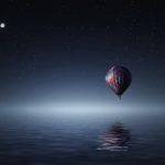 a hot air balloon floating over the water at night.