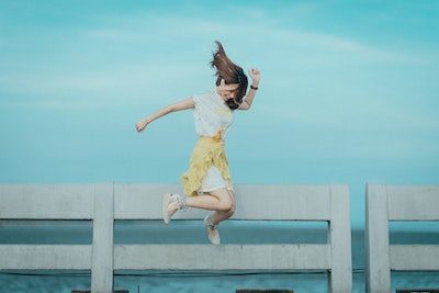 a woman jumping in the air on a bridge.