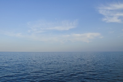 a large body of water sitting under a blue sky.