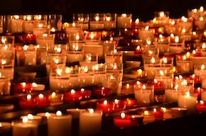 rows of lit candles in a dark room.