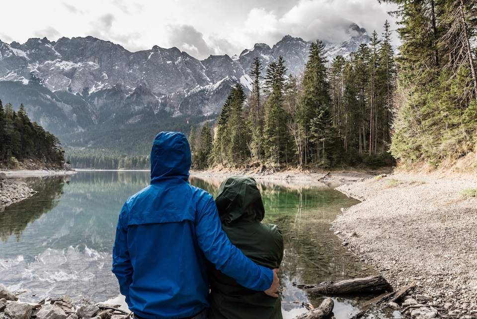 a man and a woman are looking at a mountain lake.