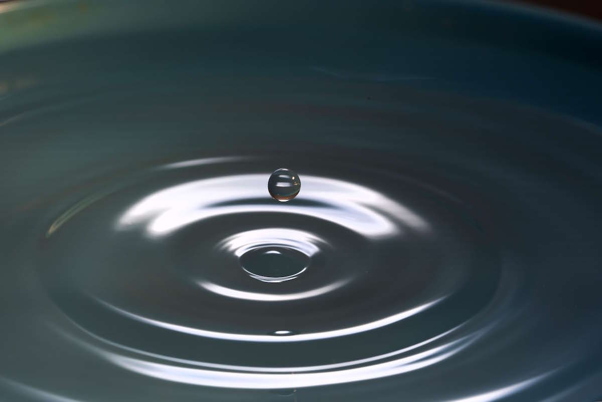 a close up of a bowl of water with a drop of water.