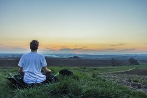 a man sitting in a field watching the sunset.