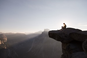 a person sitting on top of a cliff.