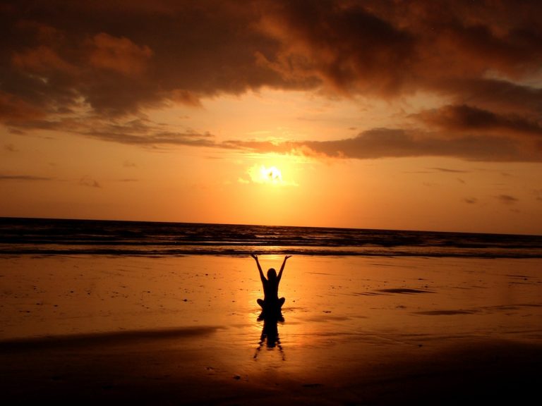 a person standing on a beach at sunset.