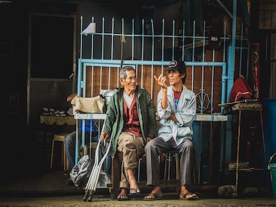 two people sitting on a bench in front of a cage.