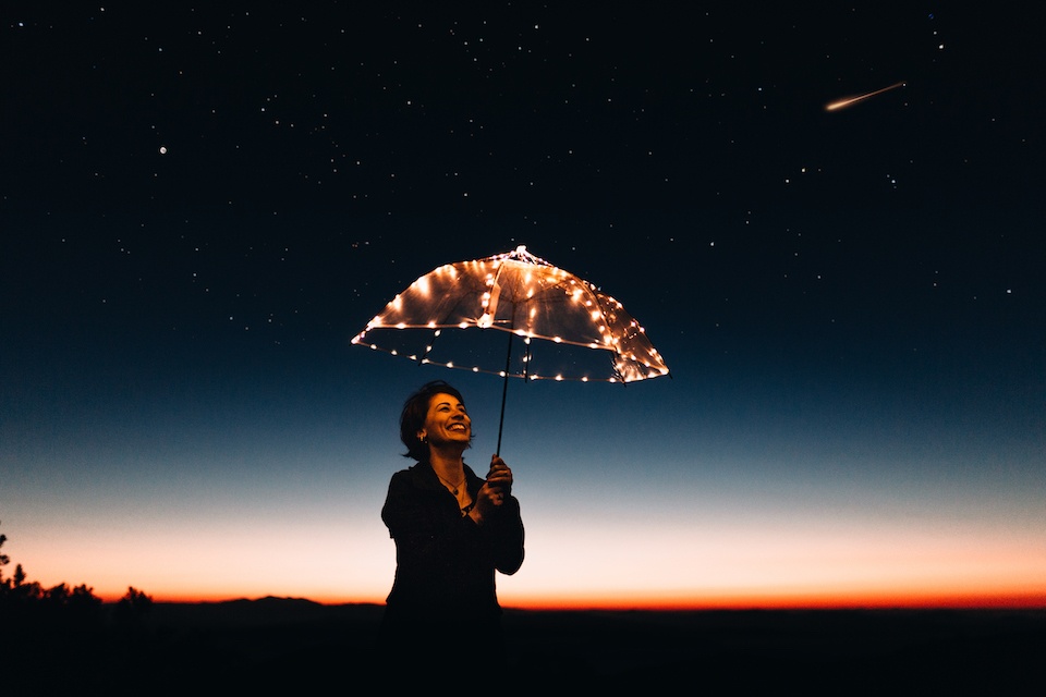 a woman holding an umbrella in the dark.