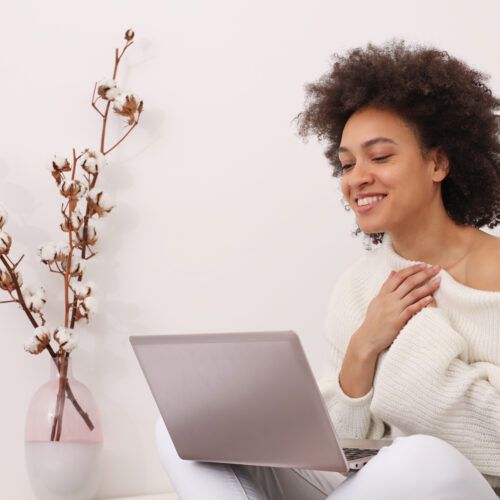 a woman sitting on a couch using a laptop computer.