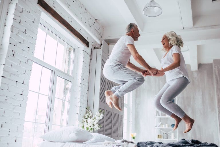 a man and a woman jumping on a bed.