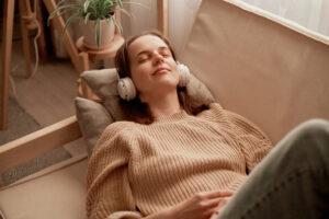 a woman laying on a couch listening to headphones.